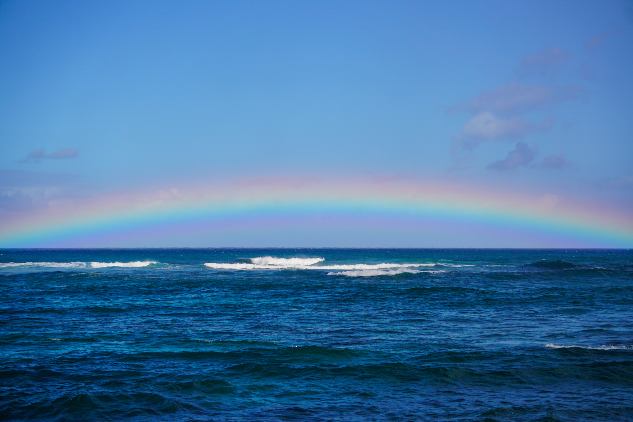 Vibrant rainbow over the blue ocean at Laniakea, Oahu Hawaii