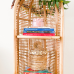 Surf books on rattan book shelf decorated with Hawaiian lei and kukui nuts