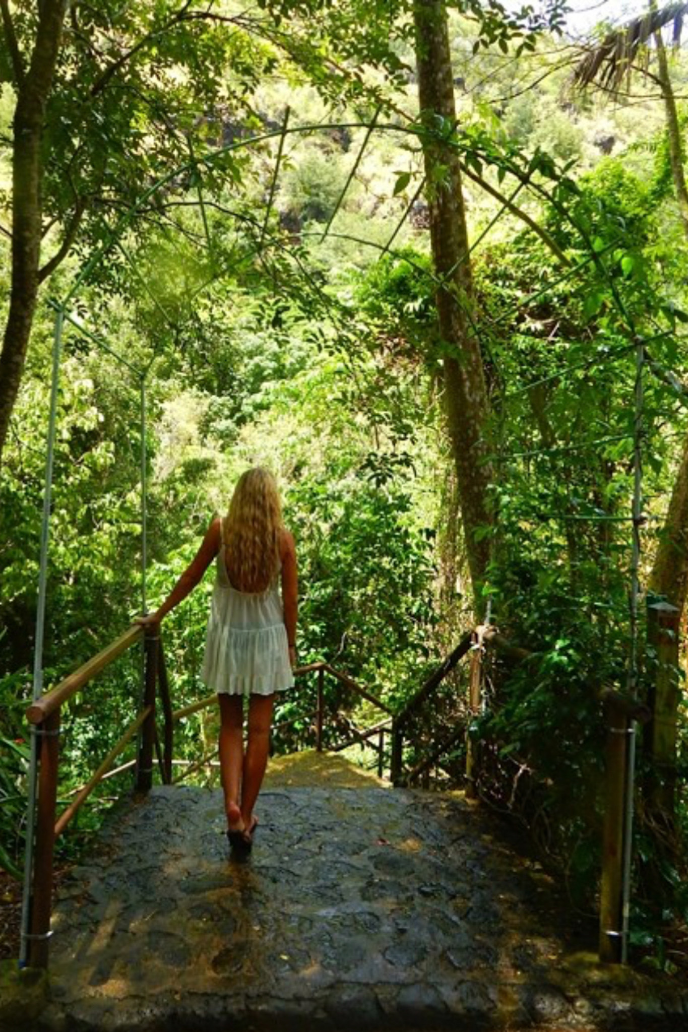 Girl in front of wire garden arch and tropical foliage